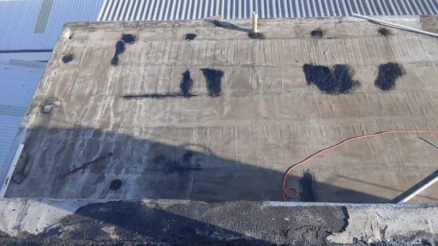 Bitumen patch repairs on a concrete flat roof to stop leaks