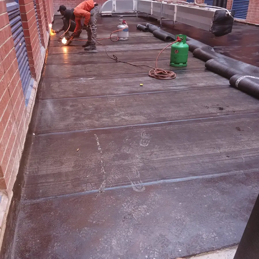 Waterproofing team installing torch-on membrane on a flat roof walkway in the Northern Suburbs